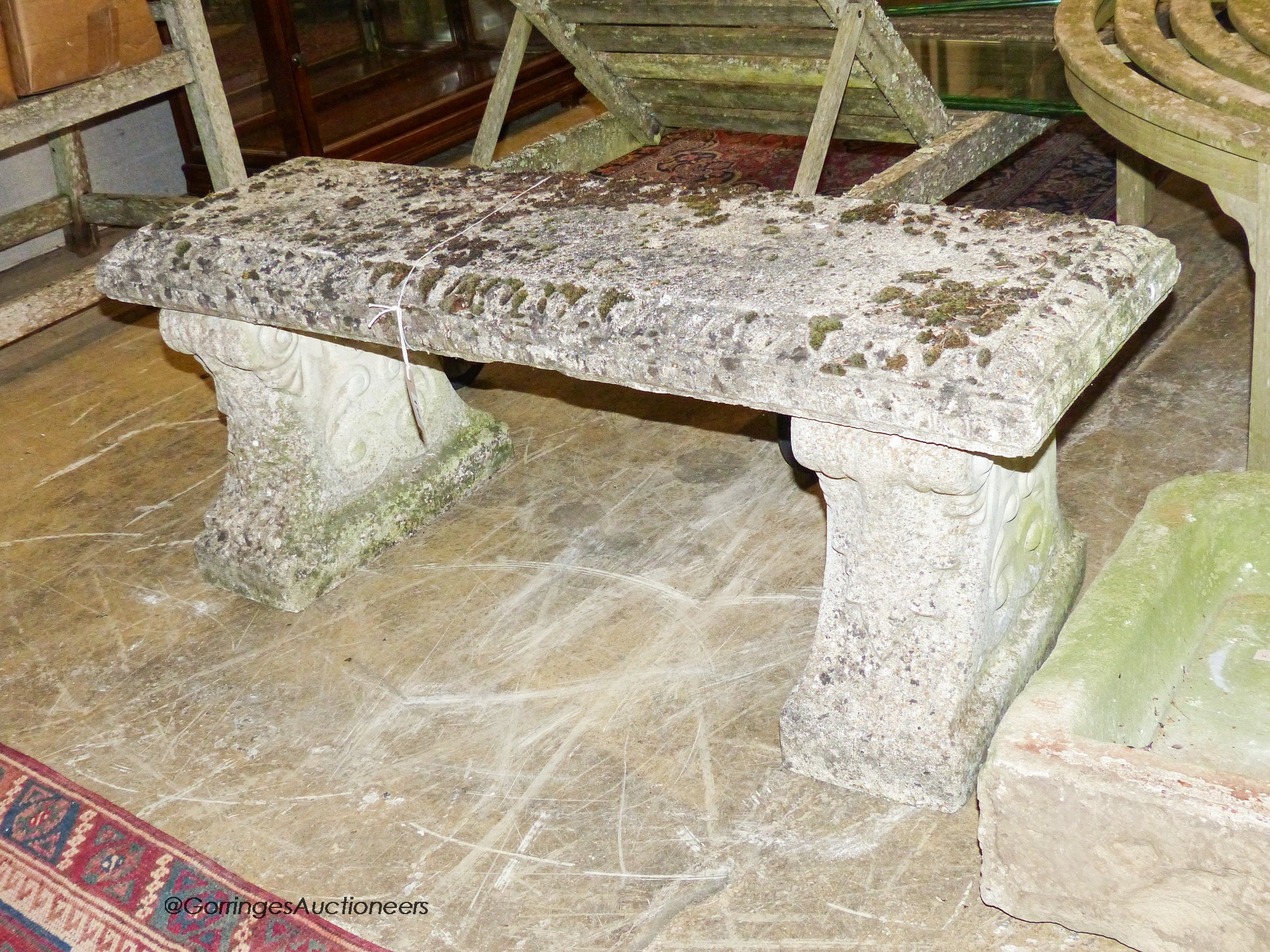 A reconstituted stone bench having moulded rectangular top on acanthus-decorated end supports, width 112cm, depth 36cm, height 42cm